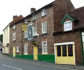 Historic brick exterior of a traditional English pub and brewery on a sloped street.