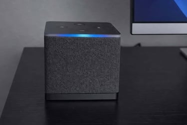 Amazon fire tv cube with fabric finish on a desk beside a computer monitor