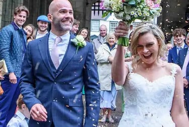 A happy bride and groom celebrate with guests as wedding confetti falls in Bury St Edmunds
