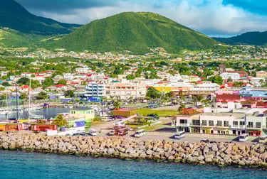 Aerial view of Basseterre harbor in St. Kitts with colorful buildings and a lush green mountain.