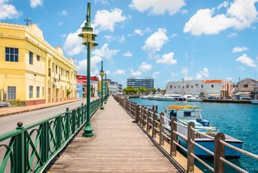 Sunny boardwalk along the Constitution Bridge riverfront in Bridgetown, Barbados with docked boats.