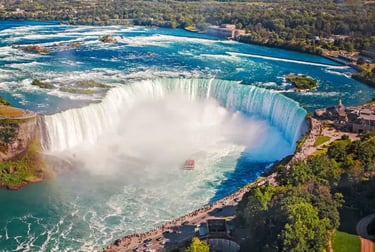 Aerial view of Horseshoe Falls at Niagara Falls with a tour boat navigating the mist-covered river.