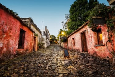 Historic cobblestone street in Colonia del Sacramento, Uruguay, with colorful colonial buildings at dusk.