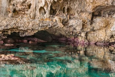 Crystal clear turquoise water reflecting rugged rock formations inside a coastal limestone sea cave.