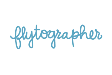 Flytographer logo in blue script font against a solid black background for professional travel photography services.