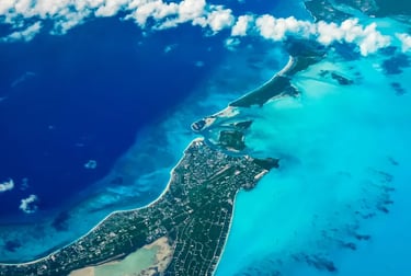 Aerial view of tropical islands surrounded by turquoise Caribbean waters and white clouds.
