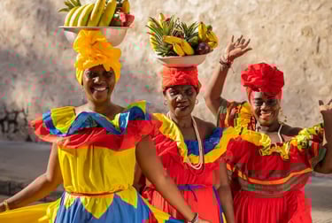 Colombian Palenqueras in traditional colorful dresses balancing fruit baskets on their heads in Cartagena.