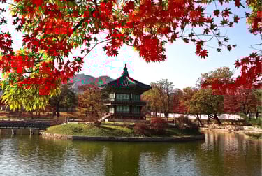Hyangwonjeong Pavilion at Gyeongbokgung Palace framed by vibrant red autumn maple leaves in Seoul.