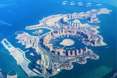 Aerial view of The Pearl-Qatar luxury man-made island featuring Porto Arabia marina and high-rise apartments.