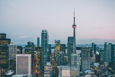 Panoramic evening view of the Toronto skyline featuring the illuminated CN Tower and downtown skyscrapers.