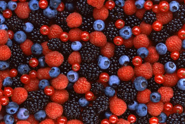 Overhead view of a fresh berry mix featuring ripe red raspberries, blueberries, and dark blackberries.