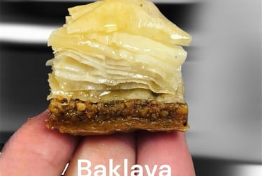 A piece of flaky Egyptian baklava with a secret sauce drizzled on crushed pistachios.