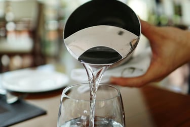 a person pouring water into a glass of water