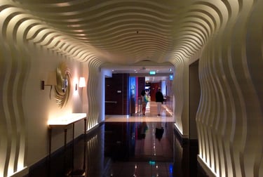 Un pasillo de hotel de lujo moderno con un techo escultórico ondulado blanco y paneles de pared 