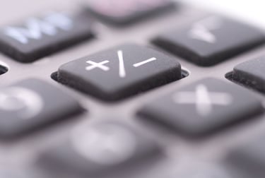 Extreme close-up of a digital calculator keypad focusing on the plus and minus arithmetic symbol keys.