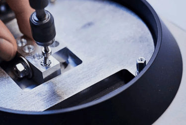 A technician using a precision tool to tighten a screw on an aluminum mechanical assembly.