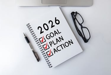 Spiral notebook with 2026 goal setting checklist including plan and action items on a white desk.