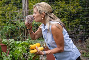 a woman in a blue shirt is holding a garlic chive blossom
