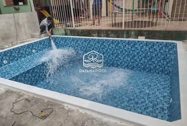 Proses pemasangan material finishing mozaik pada dinding kolam renang oleh tukang berpengalaman.