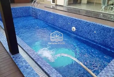 Proses pemasangan material finishing mozaik pada dinding kolam renang oleh tukang berpengalaman.
