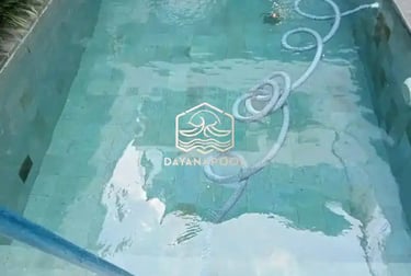 Pekerja sedang membersihkan kolam renang dengan vakum.