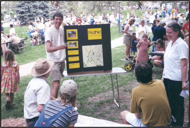 A man holding a trifold with "PedNet" information on it speaking in front of a small crowd