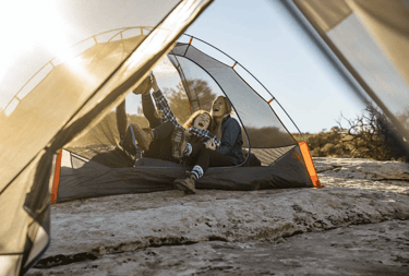 a woman sitting in a tent with her dog