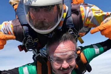 A white male doing a skydive with their disability showing