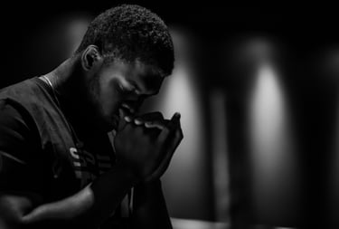 black & white photo of a Black man crossing his hands in prayer