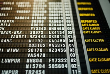 Digital airport flight departures board showing gate status and international flight schedules.