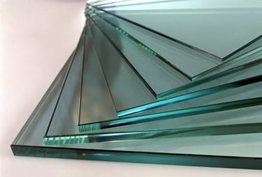Stack of thick tempered glass sheets with polished edges and blue tint for industrial construction.