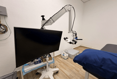 Professional ENT surgical microscope with monitor and examination bed in a medical clinic.
