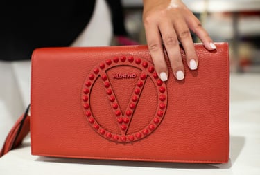 a woman's hand holding a red Valentino handbag