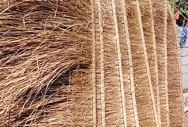 a man standing next to a pile of straw - wrapped straw - wrapped bale