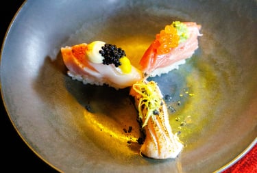 Três niguiris de sushi premium com ovas e especiarias servidos em um prato escuro no Okone Sushi Nikkei Porto.
