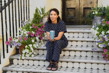 woman sitting on the stairs holding a blue cup