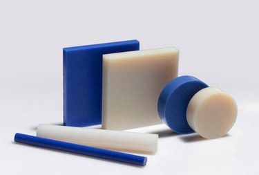 Assorted blue and white industrial plastic sheets, rods, and discs for engineering fabrication.