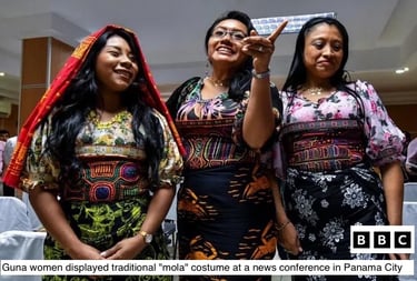 Three Guna women wear colorful traditional mola blouses and skirts at a Panama City conference.