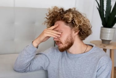 Un homme sur le canapé se tenant la tête, en proie à ses émotions avec une expression de douleur.