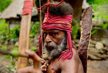 Indigenous hunter from Alor in traditional attire holding a wooden bow and arrow.