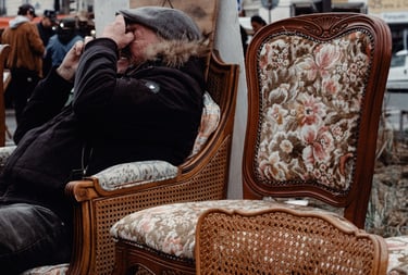 a man sitting on a chair with a hat on