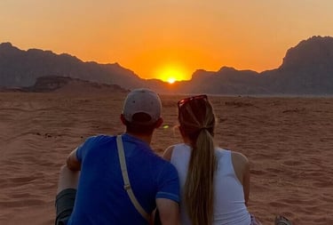 a couple sitting on a beach at sunset
