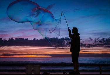 Silhouette of a man blowing giant bubbles against a sunset backdrop. Very peaceful feeling
