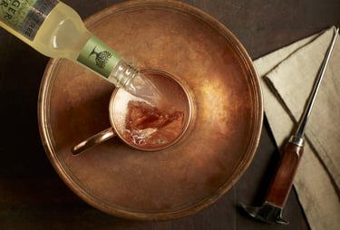           overhead image of ginger beer pouring into a copper mug