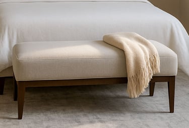 Bedroom with a bench at the foot of the bed, styled in soft lighting with neutral tones and subtle shadows.
