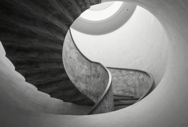 A minimalist black and white photograph of a spiral staircase, representing structure and continuous growth. High-end architectural photography.