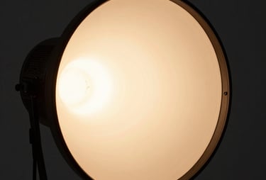 Close up shot of a film light with a terracotta gel, casting a soft warm glow in a dark studio room. Minimalist and refined.