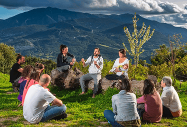 A group of people sitting in a mountain landscape during an outdoor wellness retreat session.
