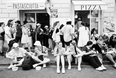 A huge crowd of tourists sit on the pavement outside a pizzeria in Rome, Italy