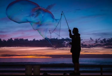Silhouette of a man blowing giant bubbles against a sunset backdrop. Very peaceful feeling